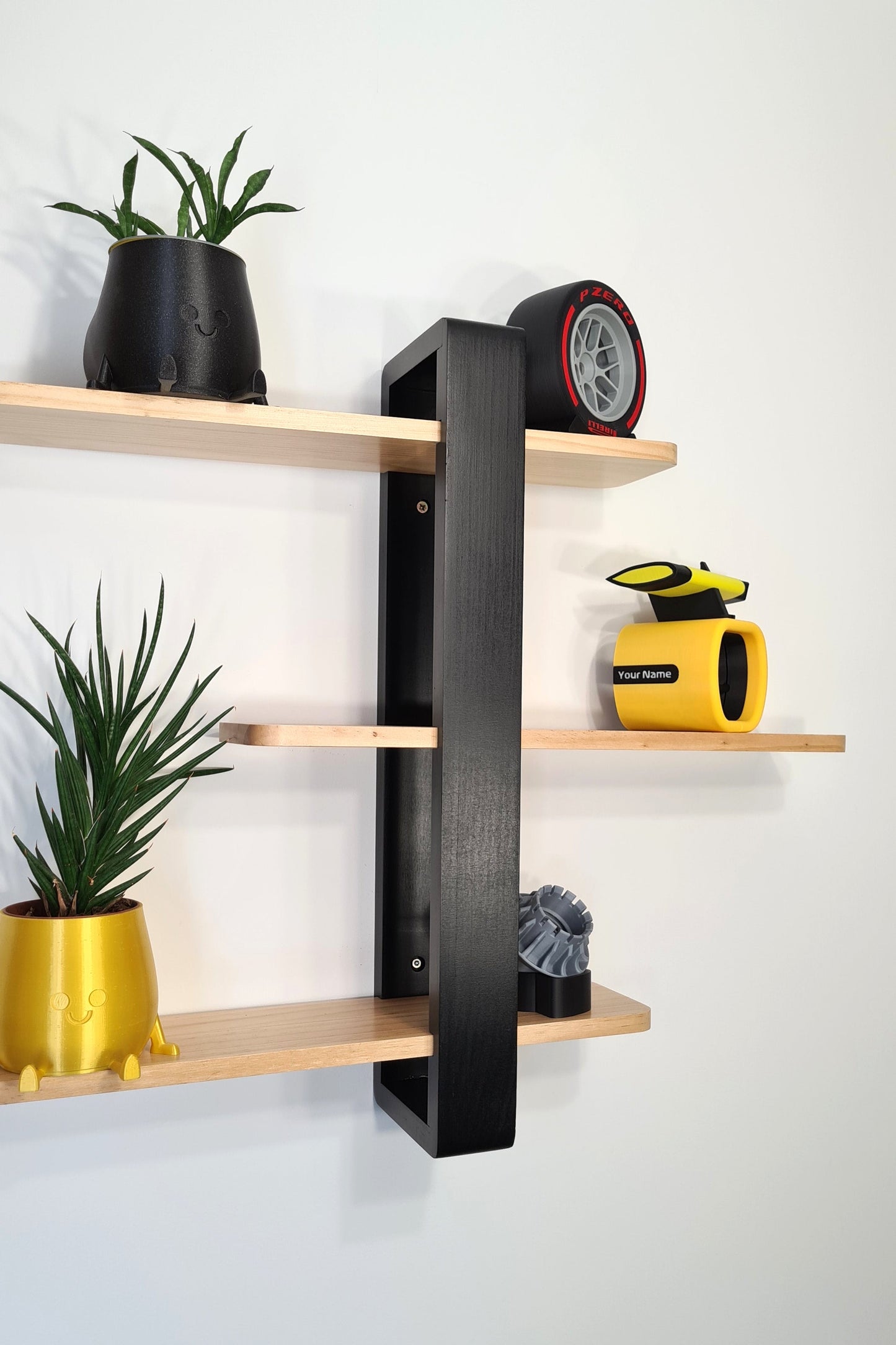 F1 motorsport decor collection on modern wood shelves, featuring Pirelli tire replica, yellow rear wing model, and wheel display.