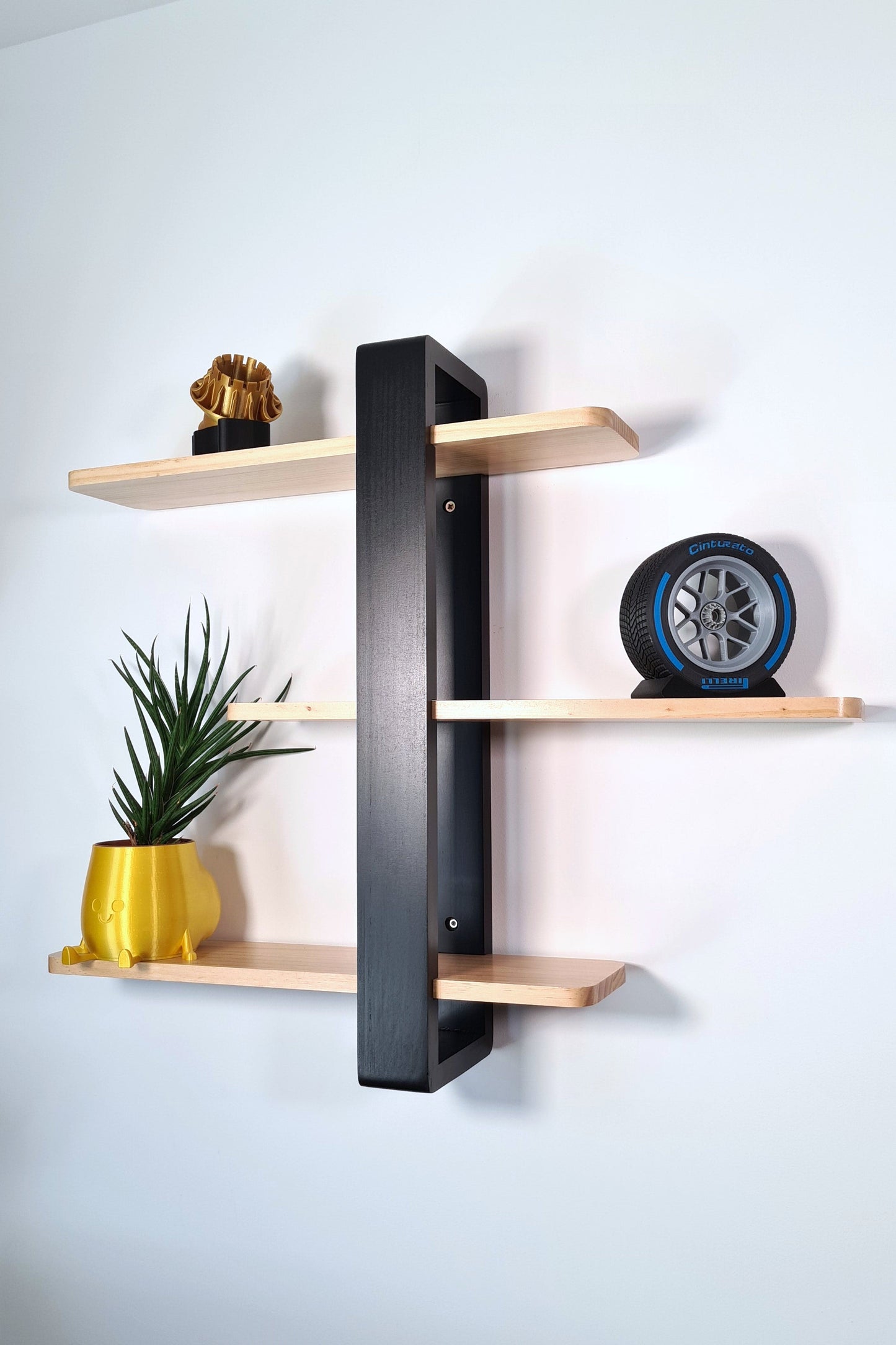 A detailed replica of an F1 wet tire and rim, placed on a black stand, featuring a silver rim with Pirelli branding and blue details on a Cinturato tire tread. Displayed against a white background with wood shelf.