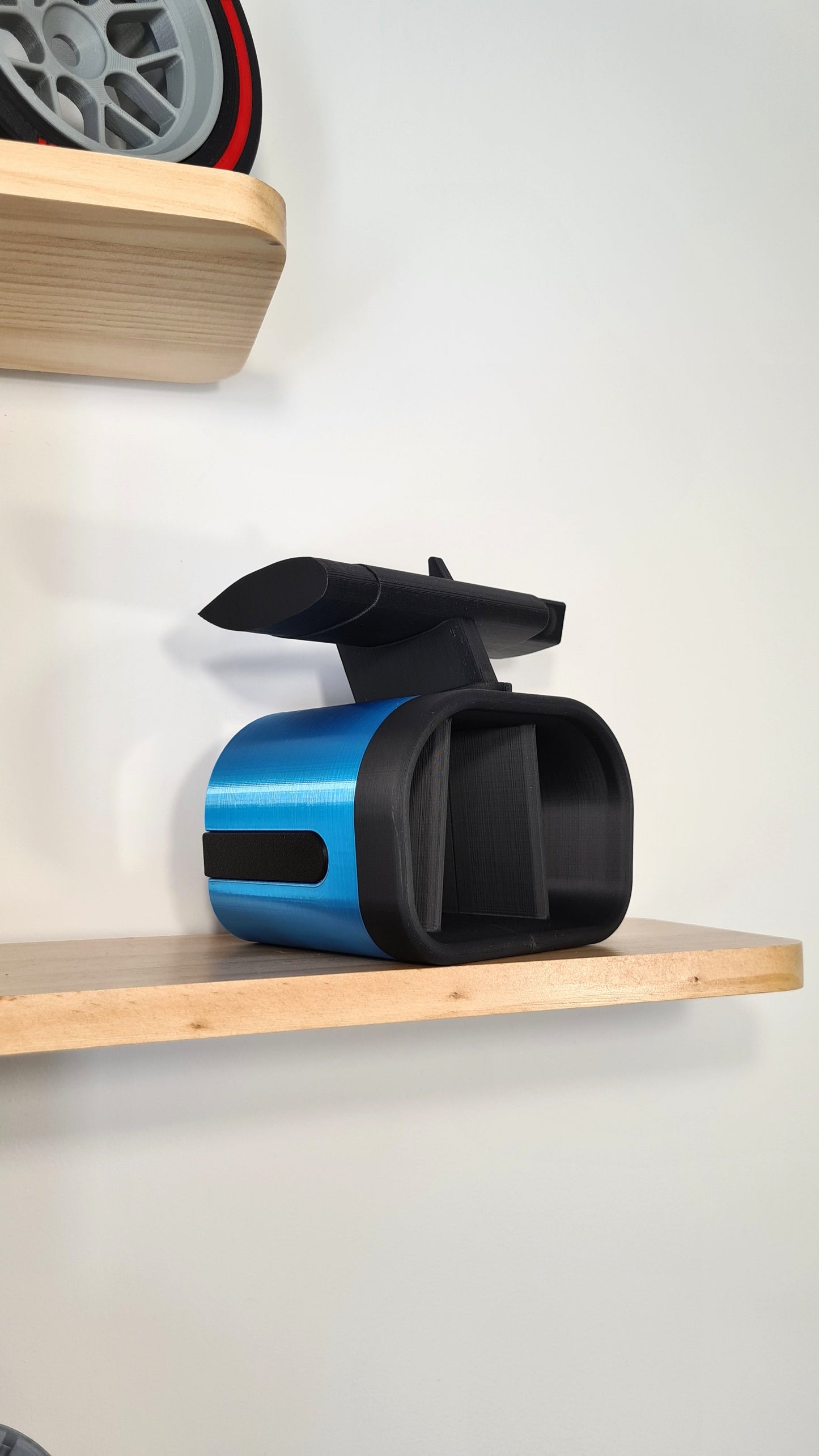 A customizable replica of an Alpine Formula 1 airbox displayed on a wooden shelf, ideal for racing enthusiasts. Emulating sleek racing design in blue and black, this model blends sporty aesthetics with collector appeal. Perfect as a unique gift.
