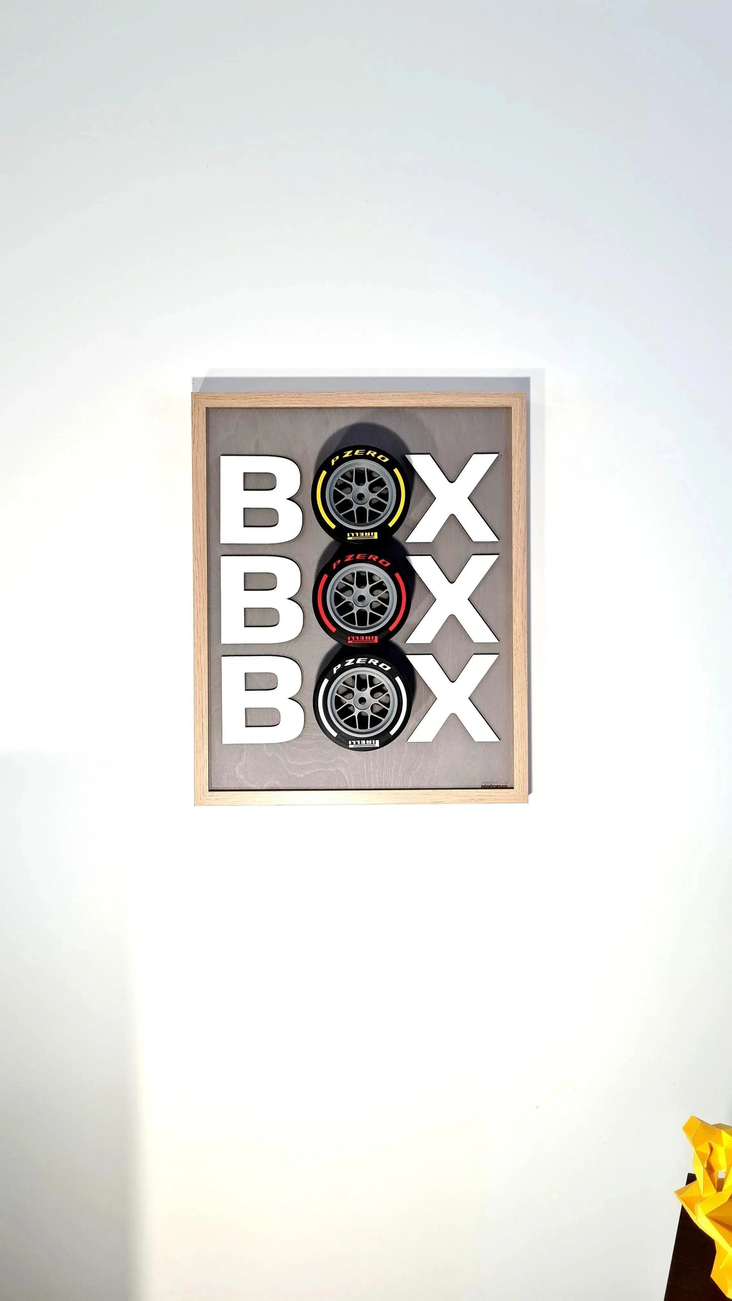 Formula 1 'BOX BOX BOX' framed wall art with Pirelli P Zero yellow, red, white tire replicas for F1 fans.