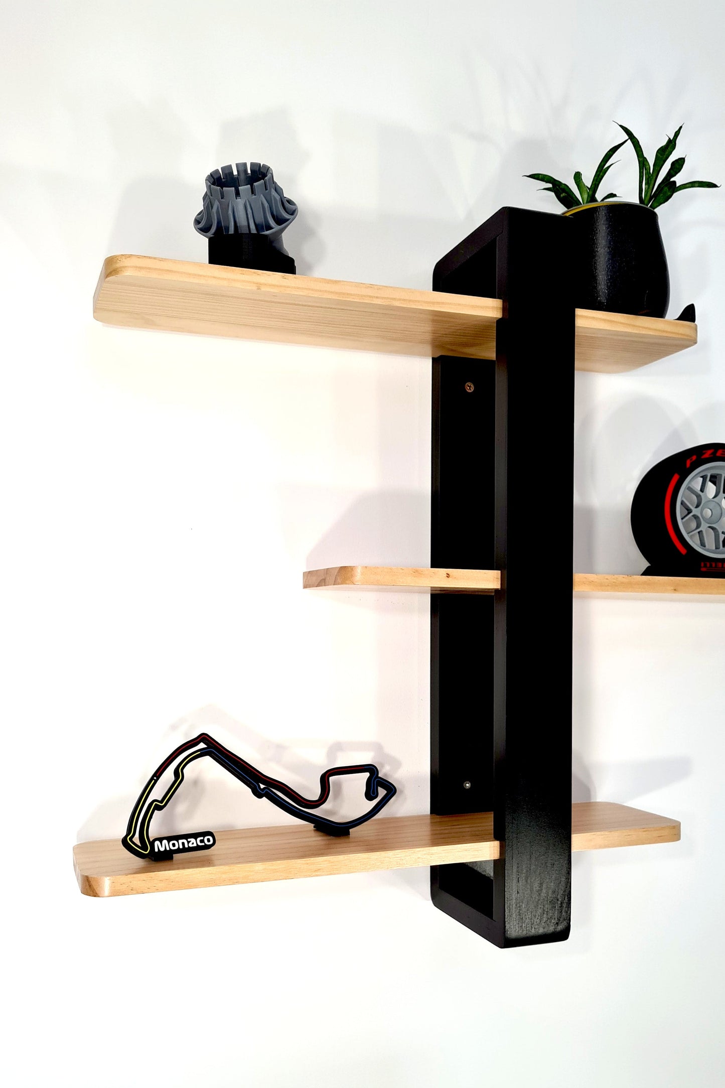 Monaco F1 circuit 3D printed track and Pirelli wheel replica on wooden display shelves, F1 fan decor.