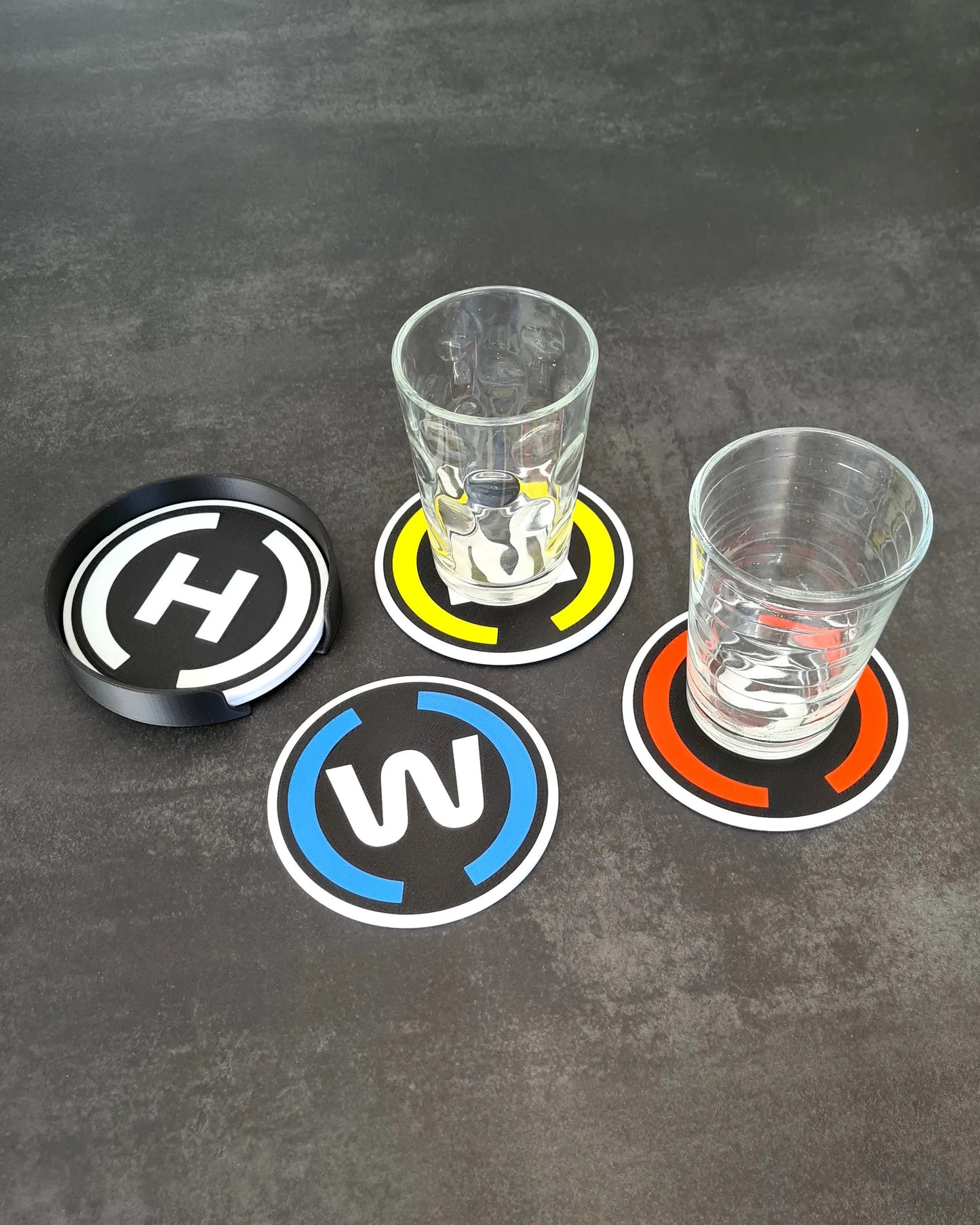 F1 driver initial coaster set with stand in black, yellow, blue, orange team colors, ideal Formula 1 fan gift.