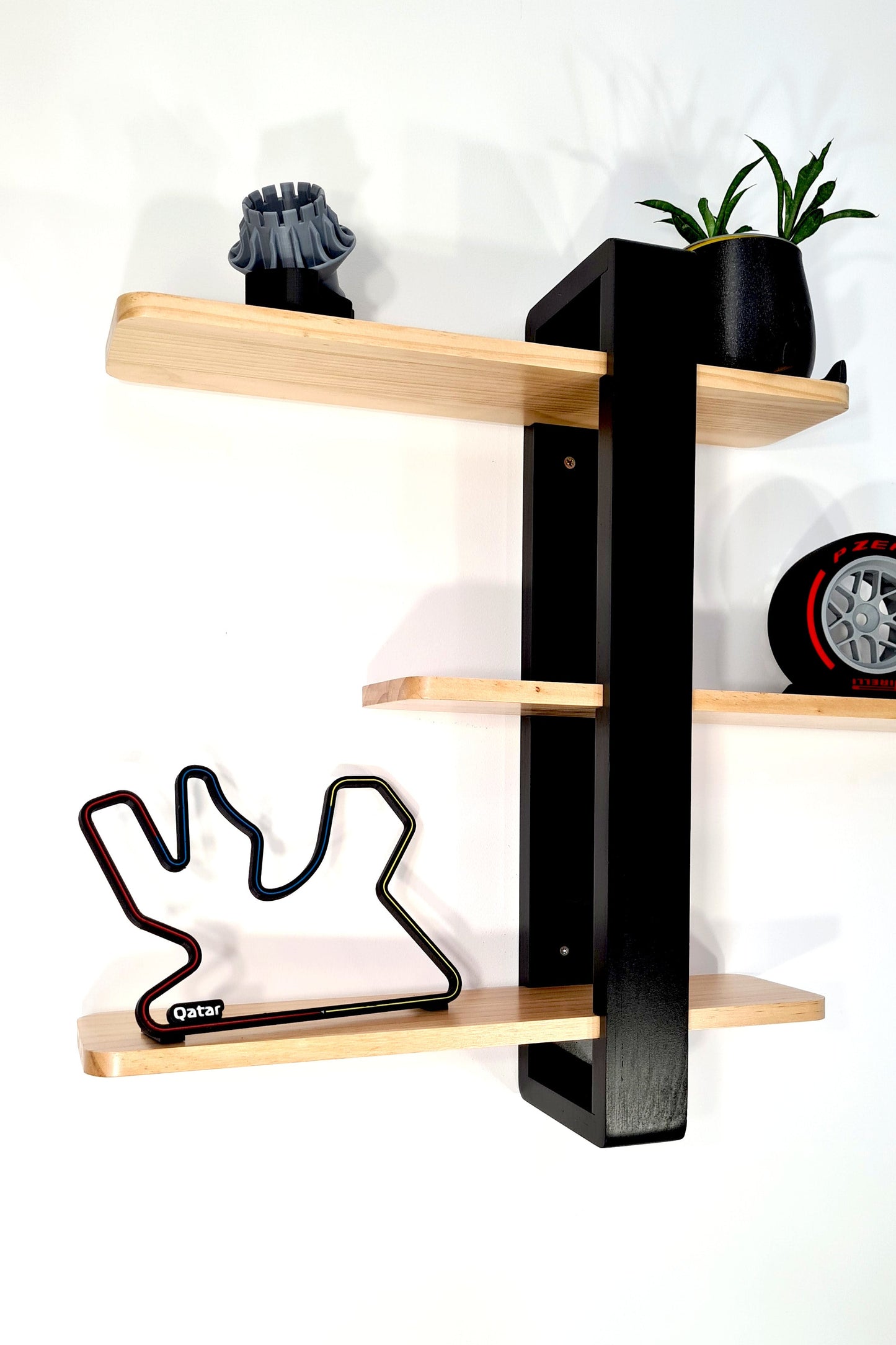 Black and natural wood F1 display wall shelf with Qatar Formula 1 circuit track art, Pirelli tire replica. Perfect motorsport fan decor.