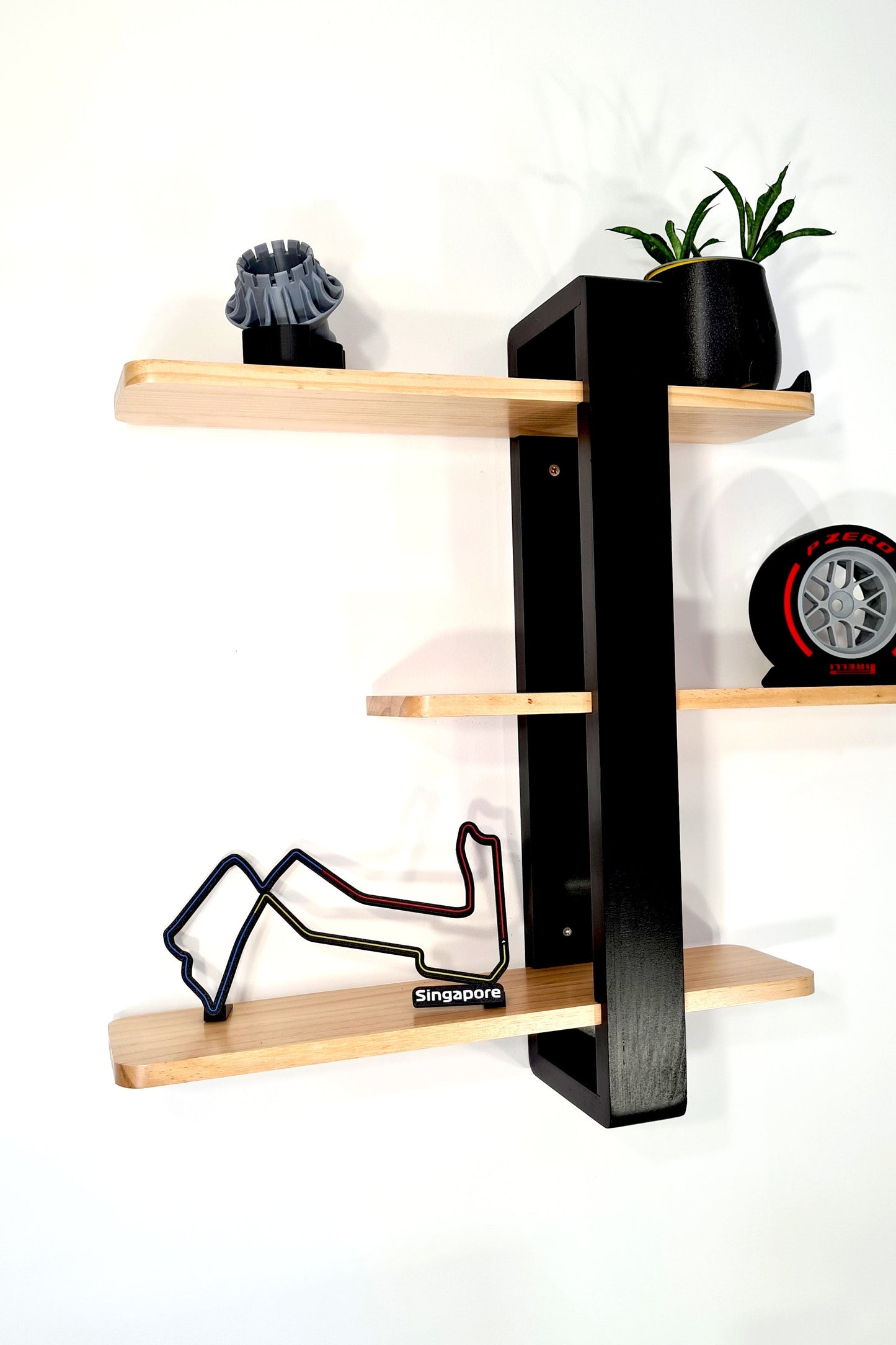 Singapore F1 circuit 3D track model, Pirelli tire replica, and turbine part on a modern display shelf.