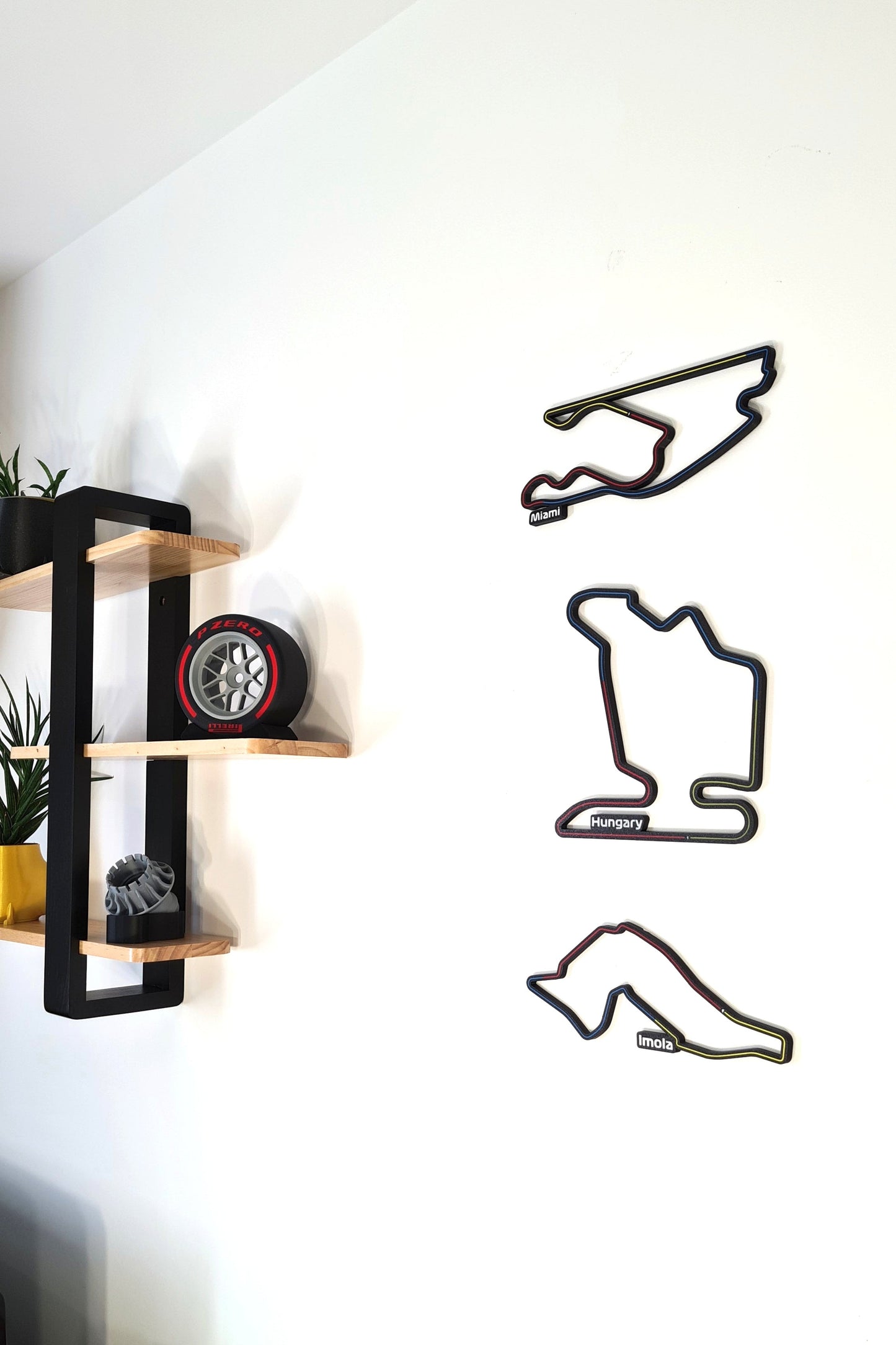 3D F1 track wall art featuring Miami, Hungary, Imola circuits, alongside a Pirelli P Zero replica tire and engine part. Great F1 fan decor.