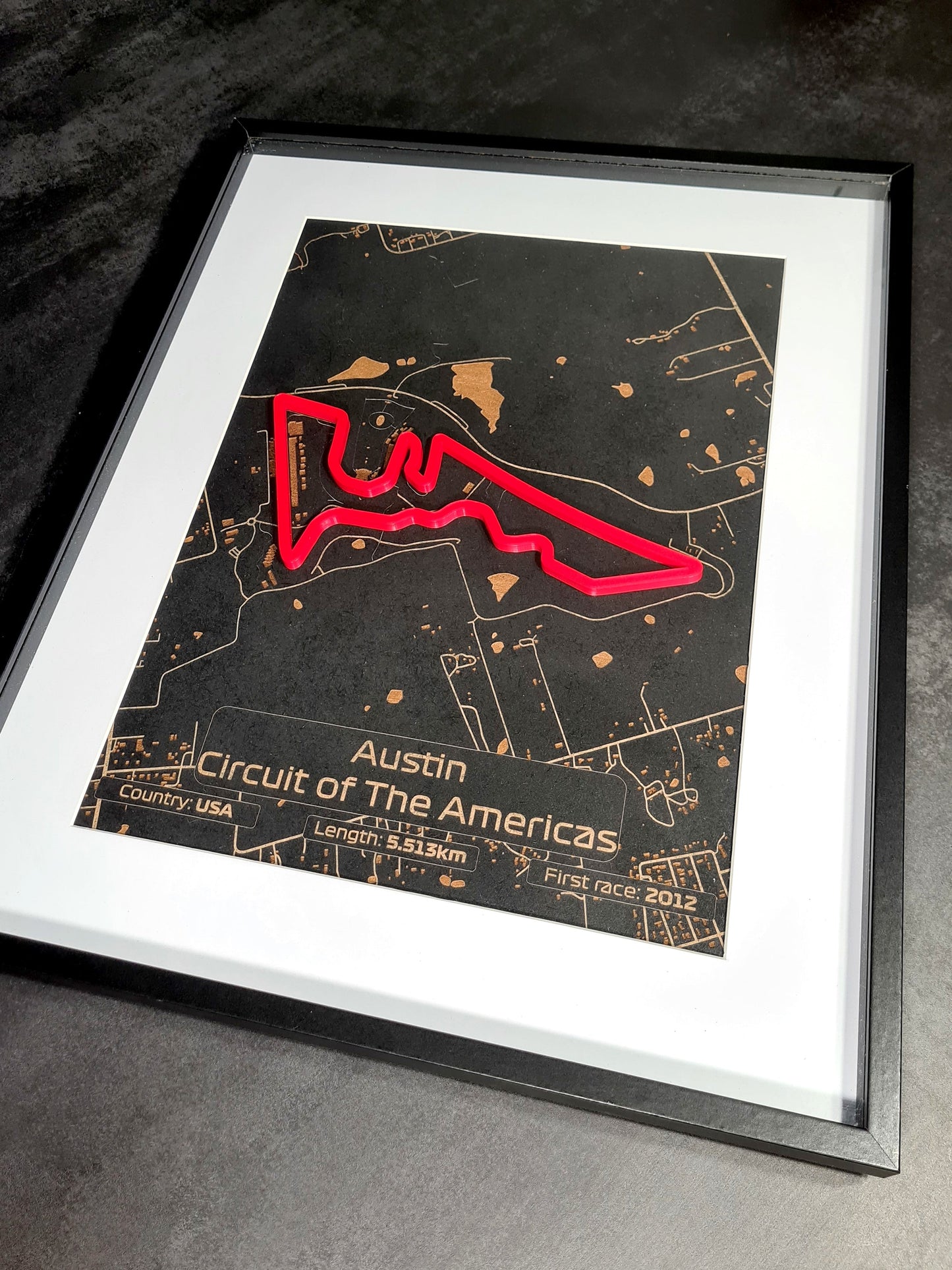 Image showcasing a framed Austin Grand Prix track with laser-cut detailing. The black frame complements the intricate metallic map design, highlighted by positive customer reviews on Etsy.
