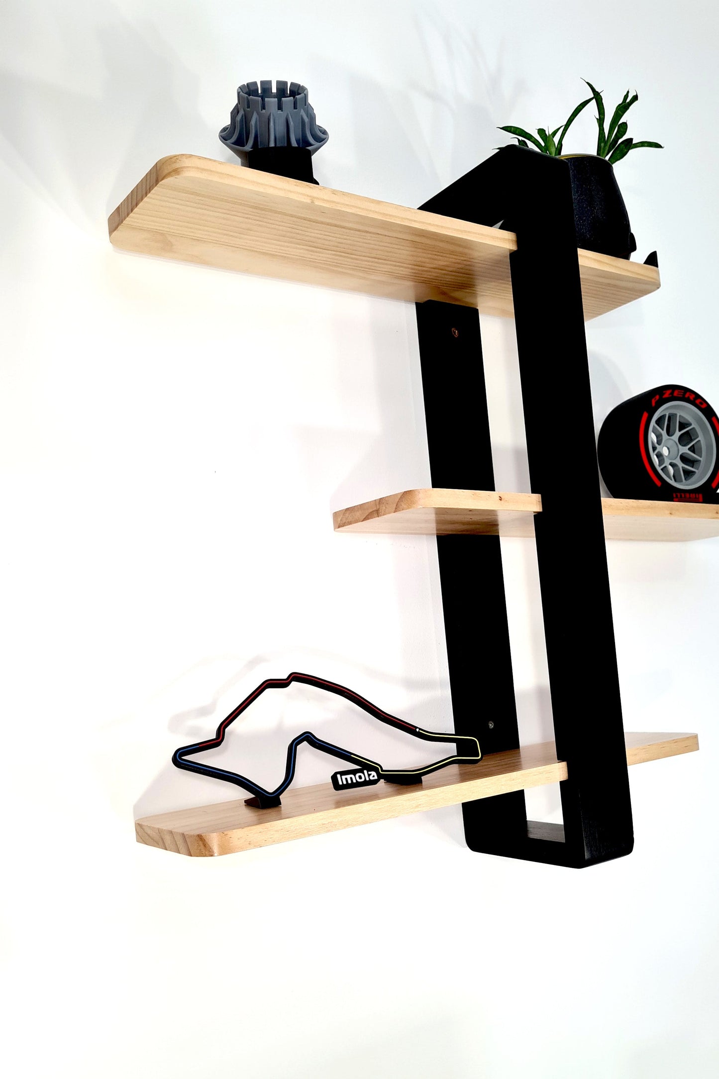 Multicolor Imola Formula 1 circuit track replica and Pirelli red sidewall F1 tire model on wooden shelf.