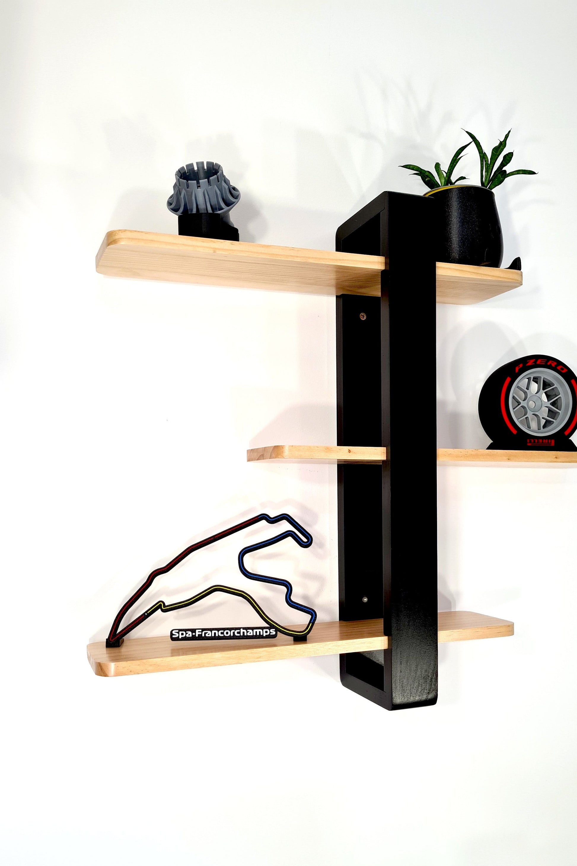Stylish black and wood wall shelf with Spa-Francorchamps F1 track, Pirelli tire replica, perfect F1 fan gift.