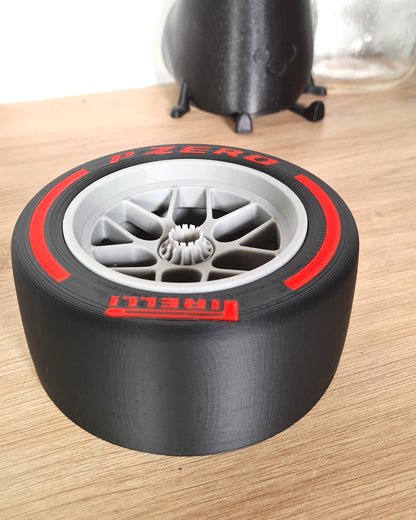 A close-up view of a 5-piece F1 wheel nut set upgrade, displayed on a wooden surface, compatible with all wheel replicas. The wheel features intricate details and bold red accents with the logo 'PIRELLI'.